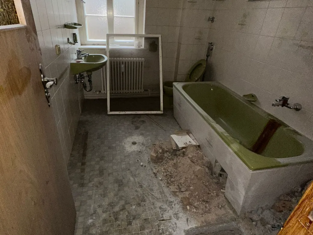 Badezimmer nach Sanierungsarbeiten mit Bauschutt auf dem Boden vor der Grundreinigung